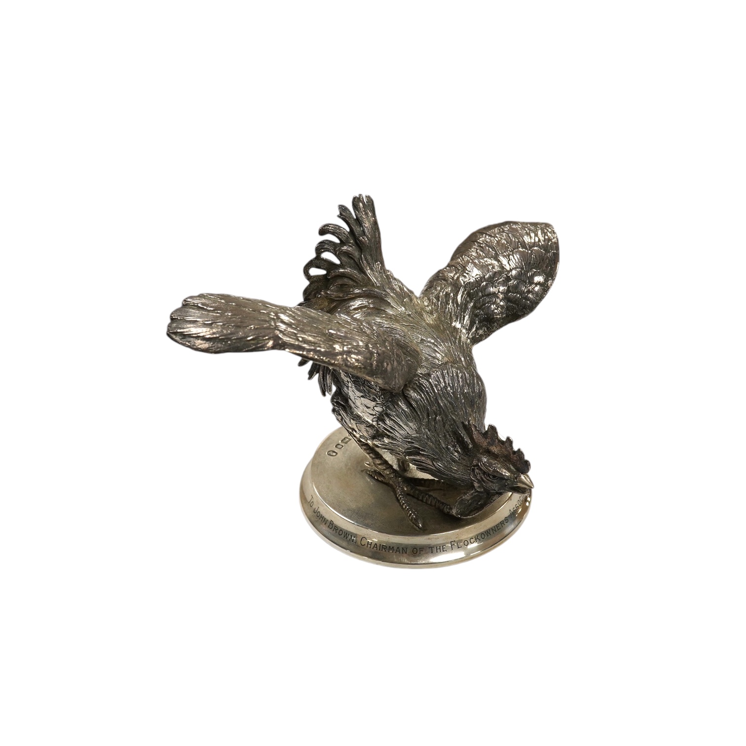 An Elizabeth II silver presentation cockerel, on a circular base with engraved inscription, by Garrard & Co Ltd, London, 1953, overall height 14cm, weighted. Condition - fair to good